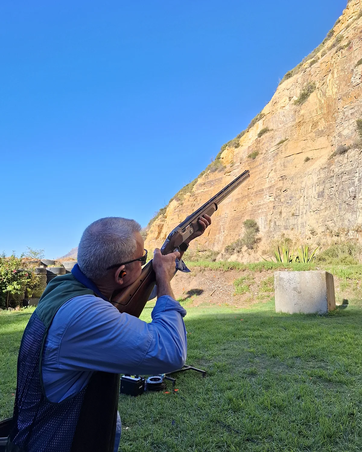 A shooter takes aim on the stand against the cliffs of the False Bay range