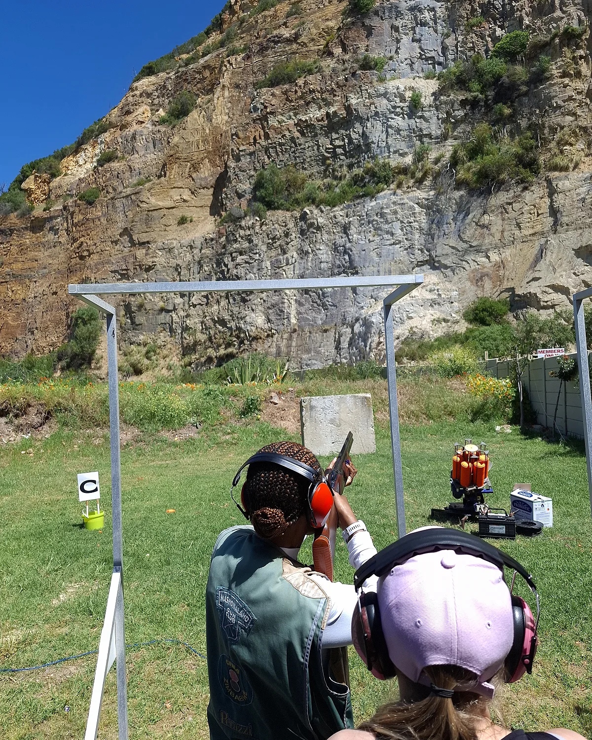 A Clay Busters instructor coaching a beginner on the stand