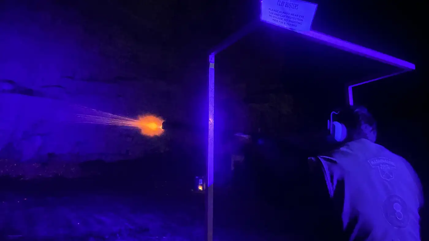 Muzzle flash lights up a night shoot in the quarry at Clay Busters
